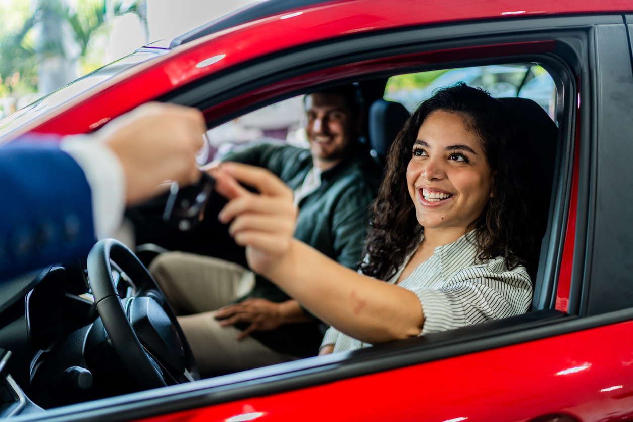 Pareja recibe las llaves de un auto rojo